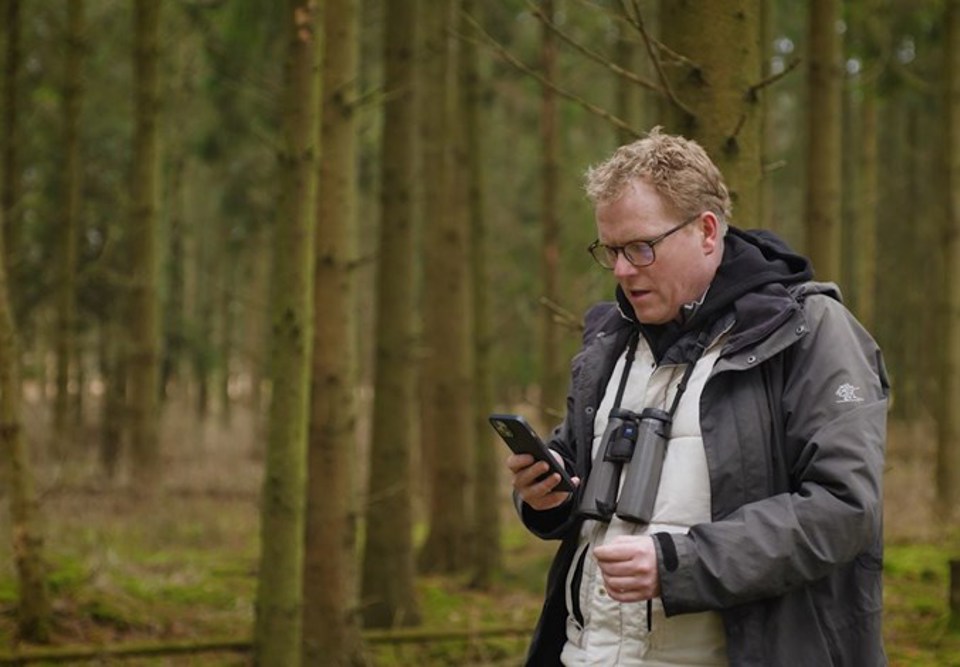 Sebastian Klein står i skoven med telefonen i hånden